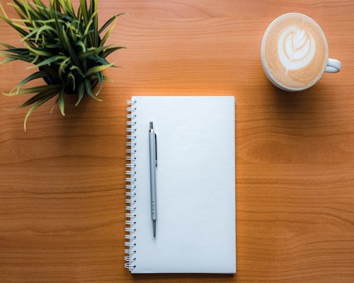 A quiet cafe table with a notebook and pen ready for writing