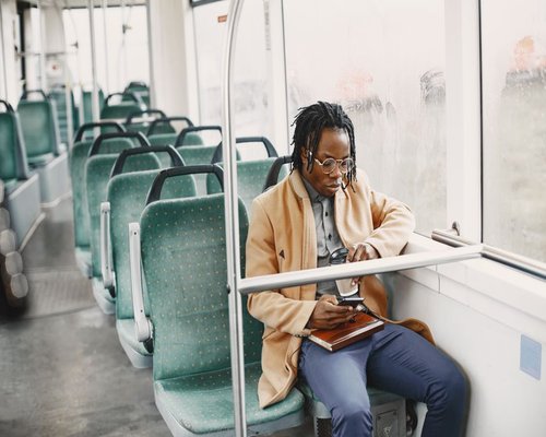Person holding a smartphone while sitting on a public bus looking out the window