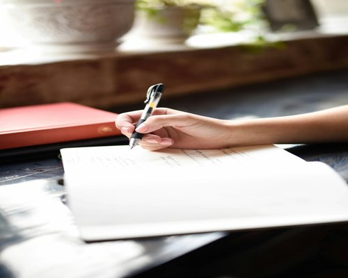 Close up of a hand checking a list in a notebook with a pen